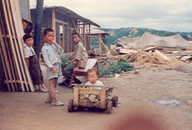 Children in tent village. Note new and old construction materials