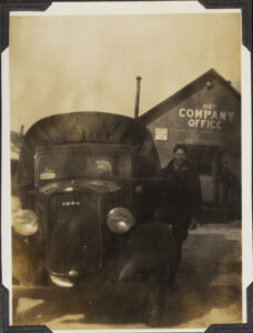 Photograph of J.P. Konsevich standing next to truck, outside the 116th Company Office building in Wendell State Forest