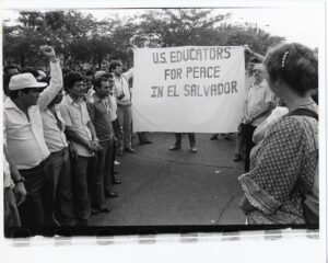 Two men holding a banner that reads "U.S. Educators for Peace in El Salvador" in a crowd