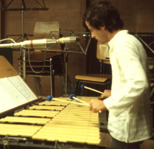 Bobby Naughton playing a vibraphone in a recording studio. He is holding three mallets.